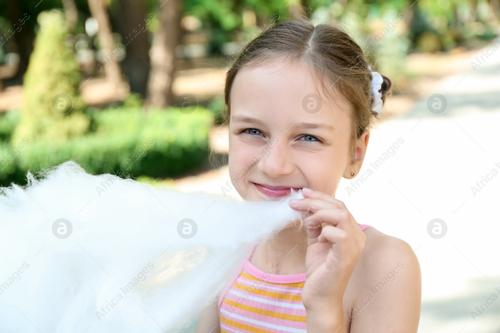 Photo of Portrait of little girl with sweet cotton candy in park