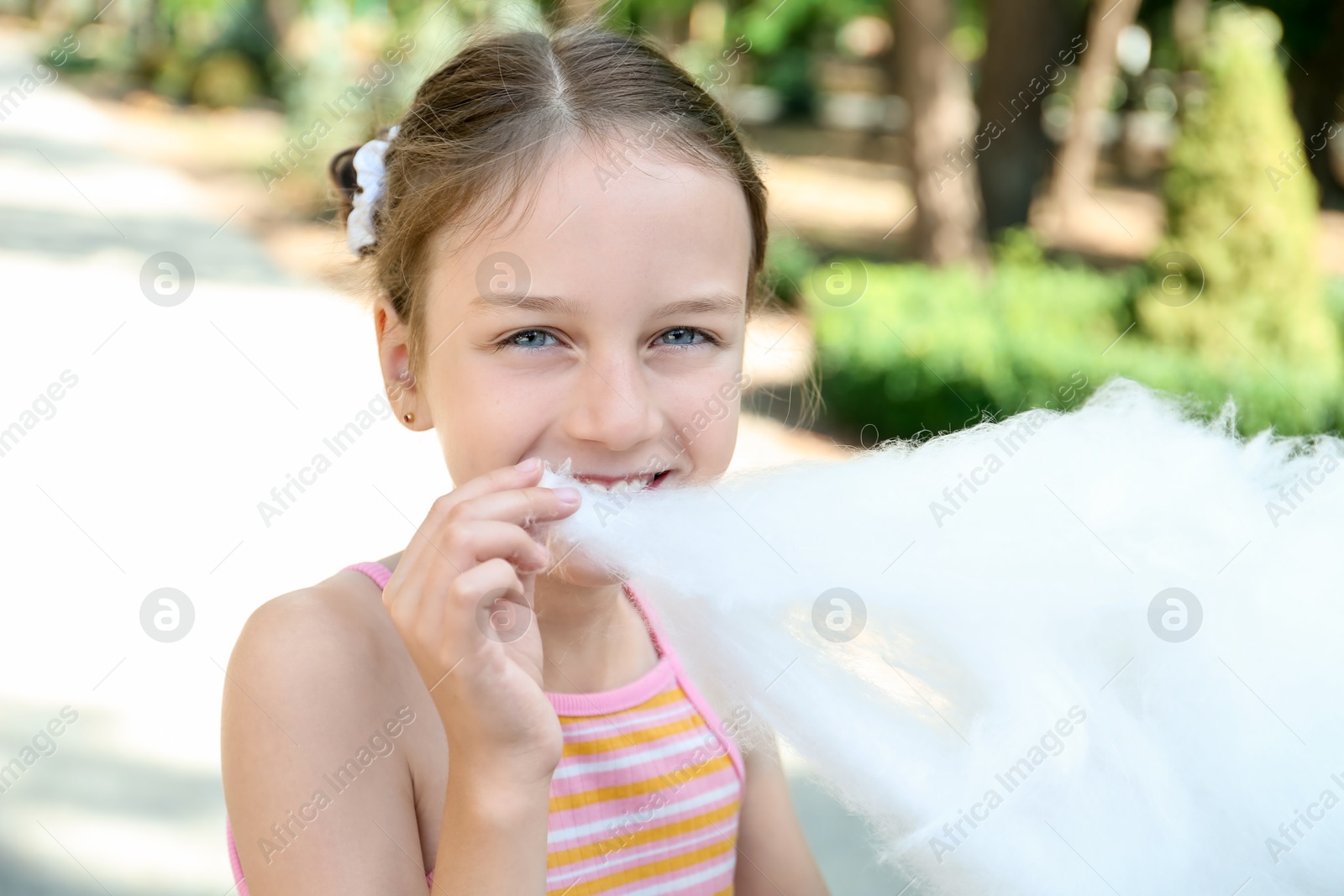 Photo of Portrait of little girl eating sweet cotton candy in park