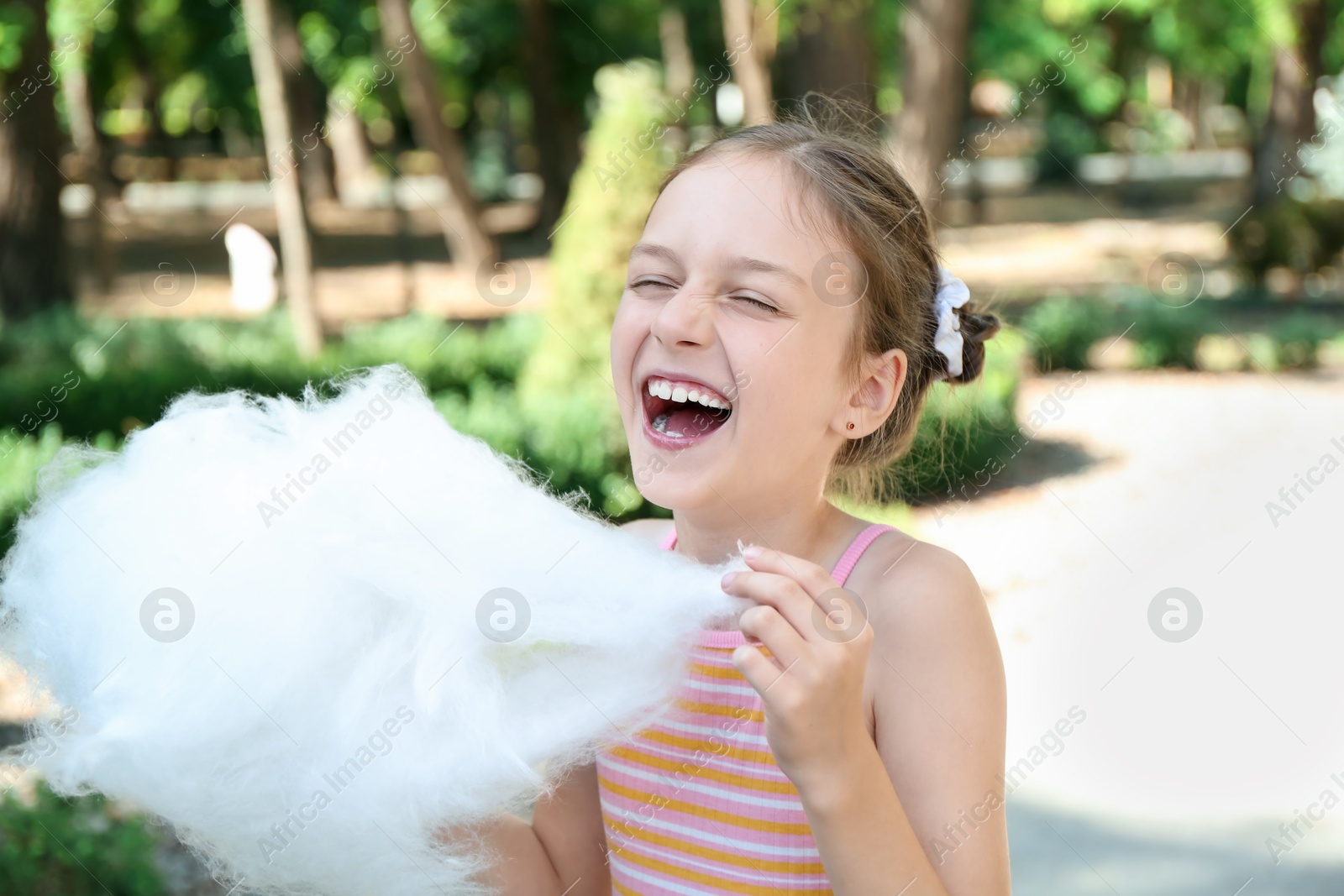 Photo of Portrait of little girl with sweet cotton candy in park