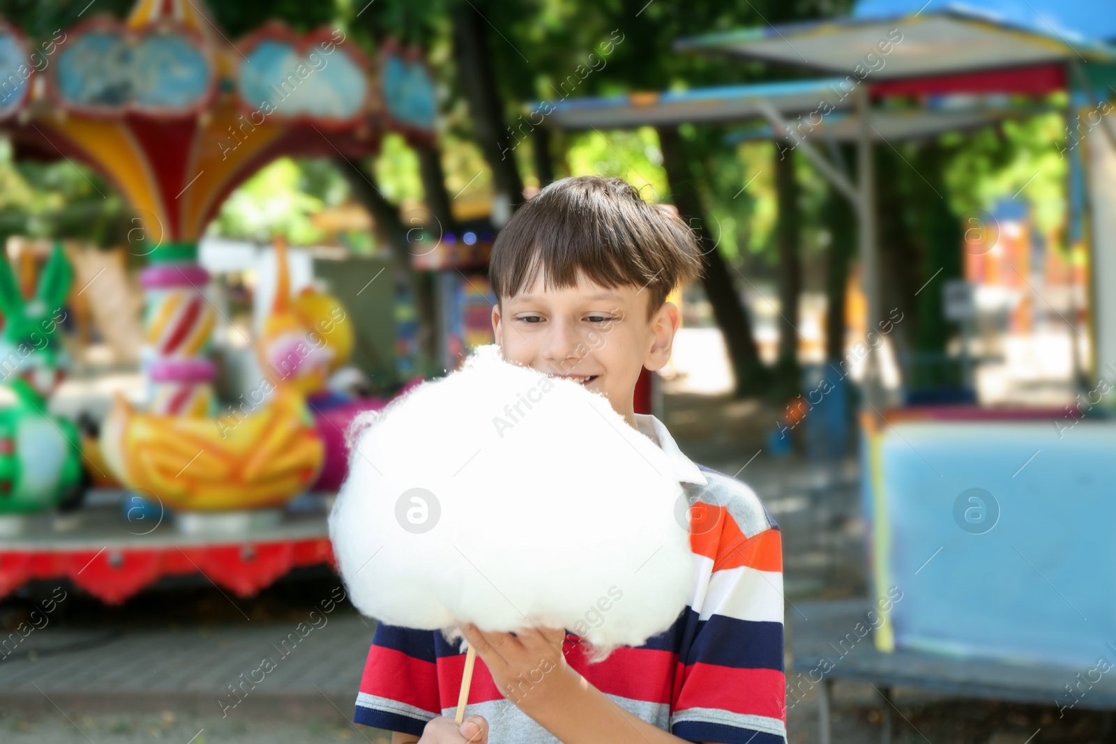 Photo of Portrait of little boy eating sweet cotton candy in park