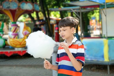 Photo of Portrait of little boy eating sweet cotton candy in park