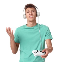 Unhappy young man in headphones with controller on white background