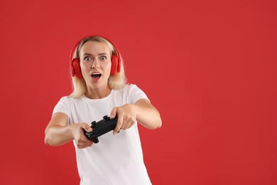 Woman in headphones playing video games with controller on red background