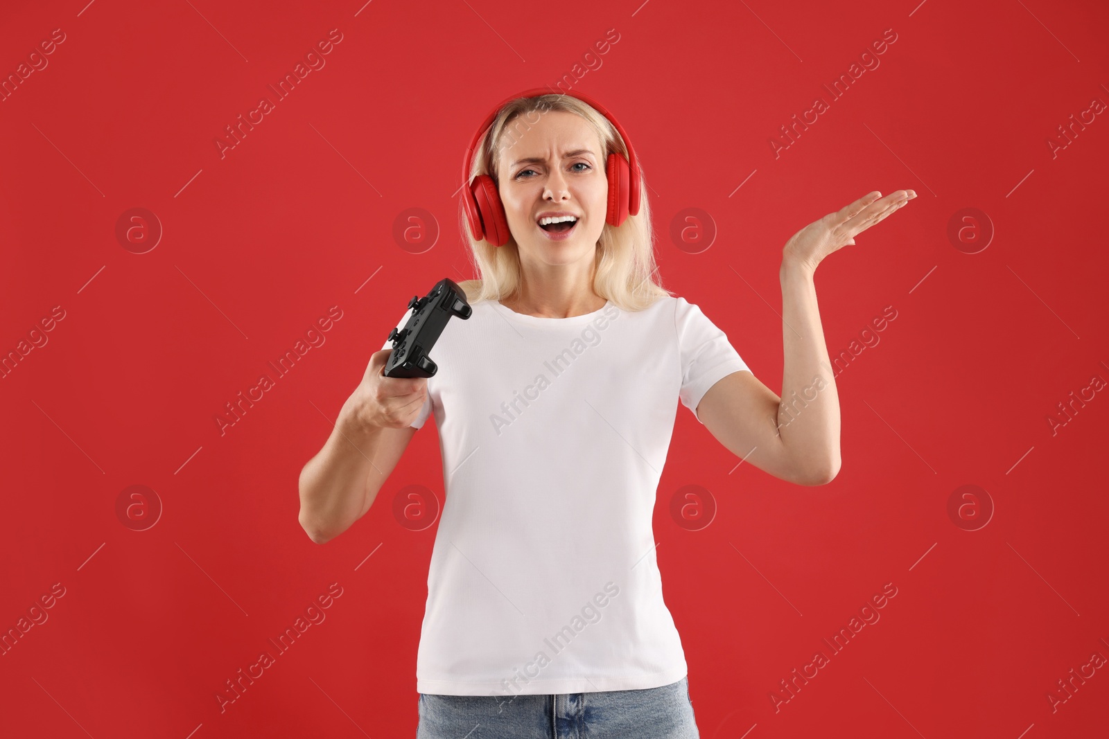 Photo of Unhappy woman with controller on red background