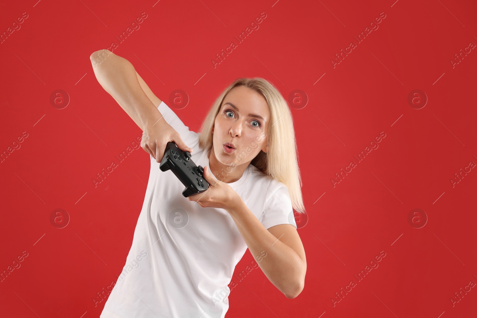 Photo of Excited woman playing video games with controller on red background