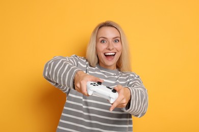 Photo of Happy woman playing video games with controller on orange background