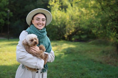 Photo of Smiling woman with cute dog in autumn park. Space for text