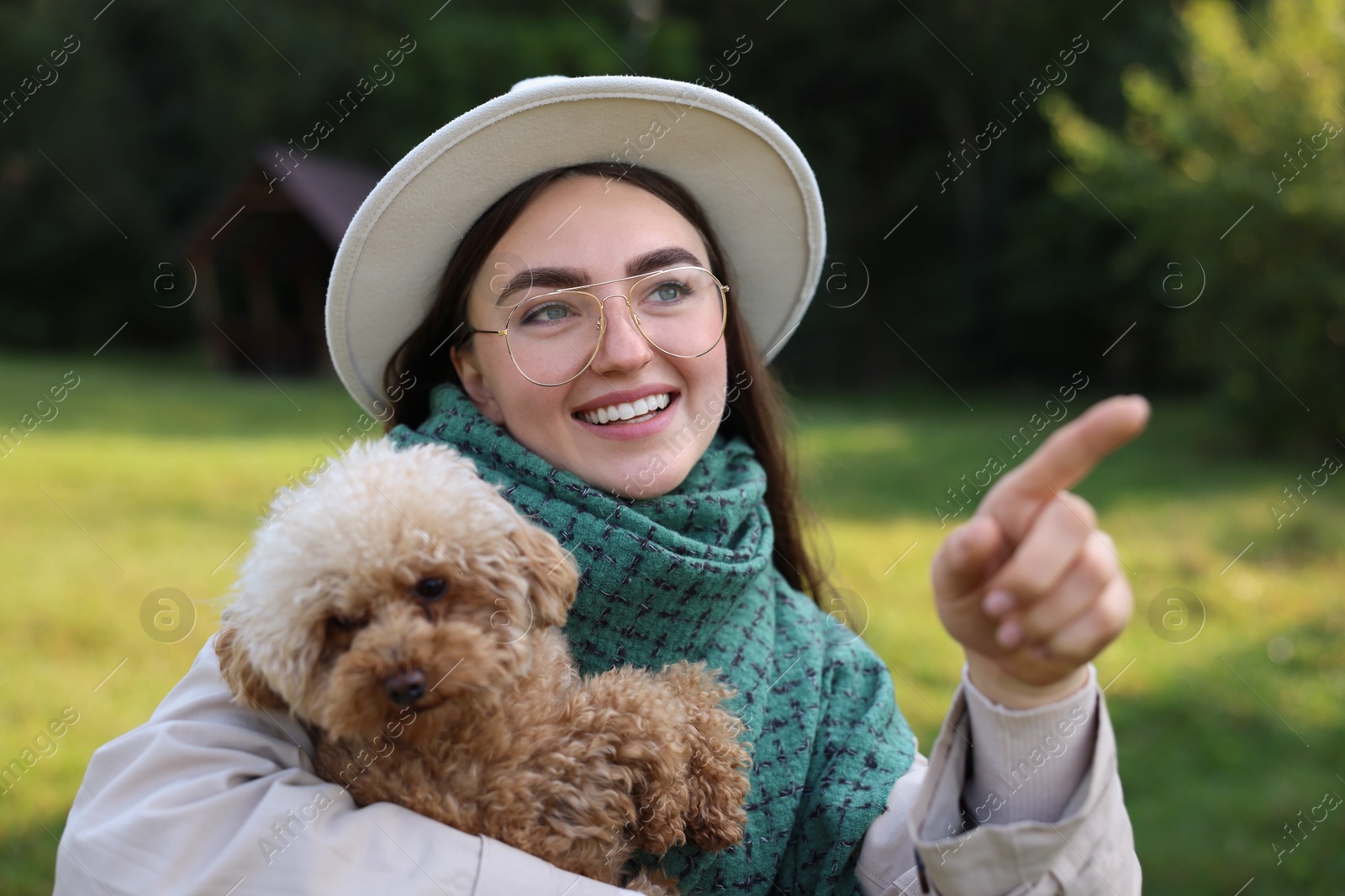 Photo of Smiling woman pointing at something to cute dog in autumn park