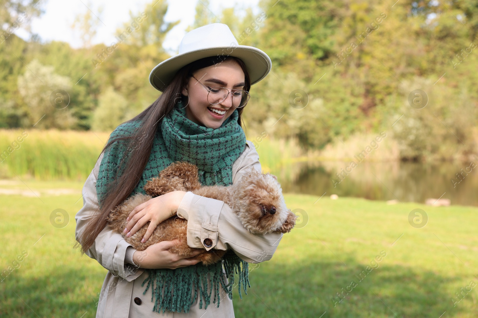 Photo of Smiling woman with cute dog in autumn park. Space for text