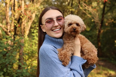 Smiling woman with cute dog in autumn park