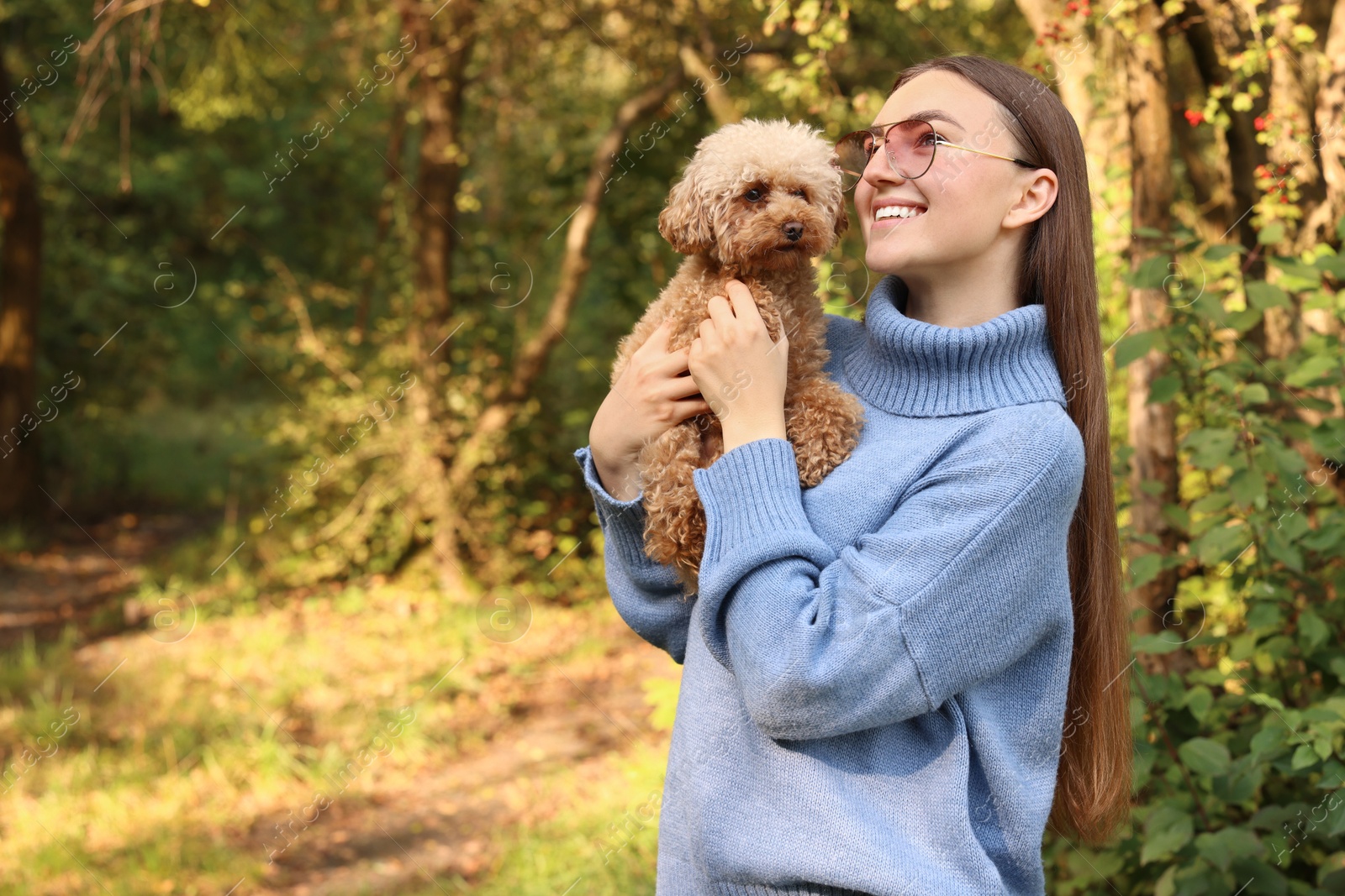 Photo of Smiling woman with cute dog in autumn park. Space for text