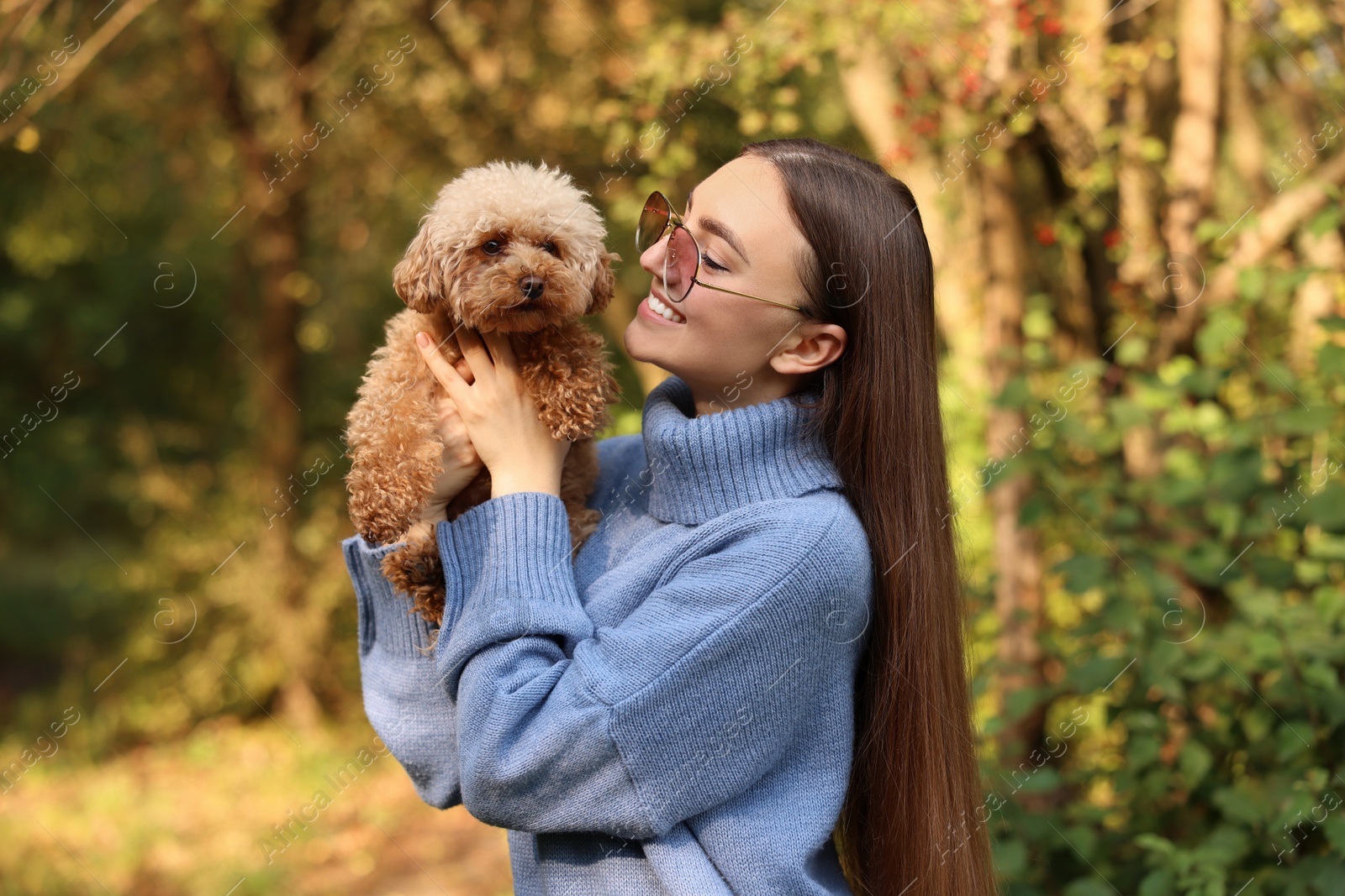 Photo of Smiling woman with cute dog in autumn park