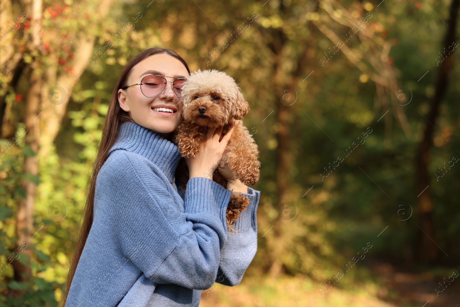 Photo of Smiling woman with cute dog in autumn park. Space for text