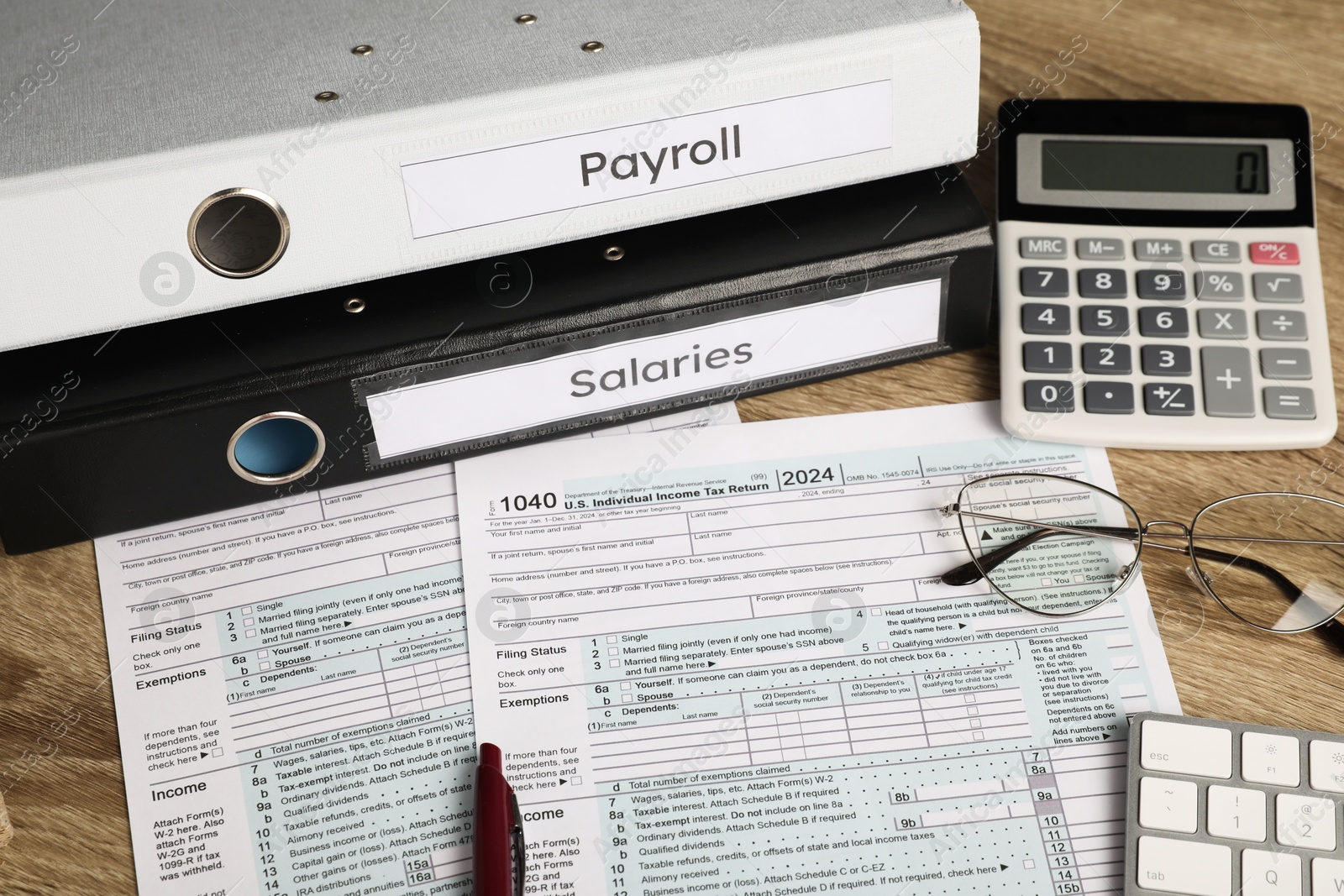 Photo of Payroll. Glasses, pen, calculator and papers on wooden table