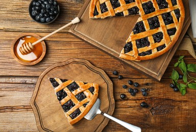 Photo of Tasty homemade pie with blueberries served on wooden table, flat lay