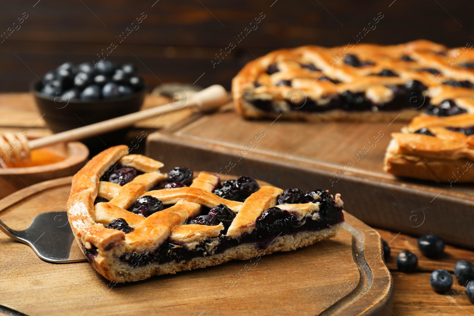 Photo of Piece of tasty homemade pie with blueberries served on wooden table, closeup