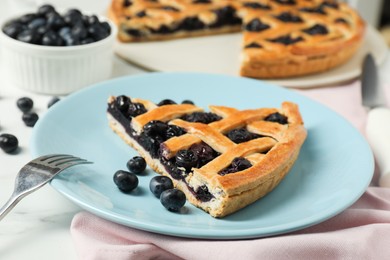 Photo of Piece of tasty homemade pie with blueberries served on white table, closeup