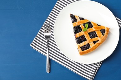 Photo of Piece of tasty homemade pie with blueberries served on blue wooden table, flat lay