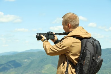 Photo of Photographer with backpack and camera taking picture of beautiful mountains