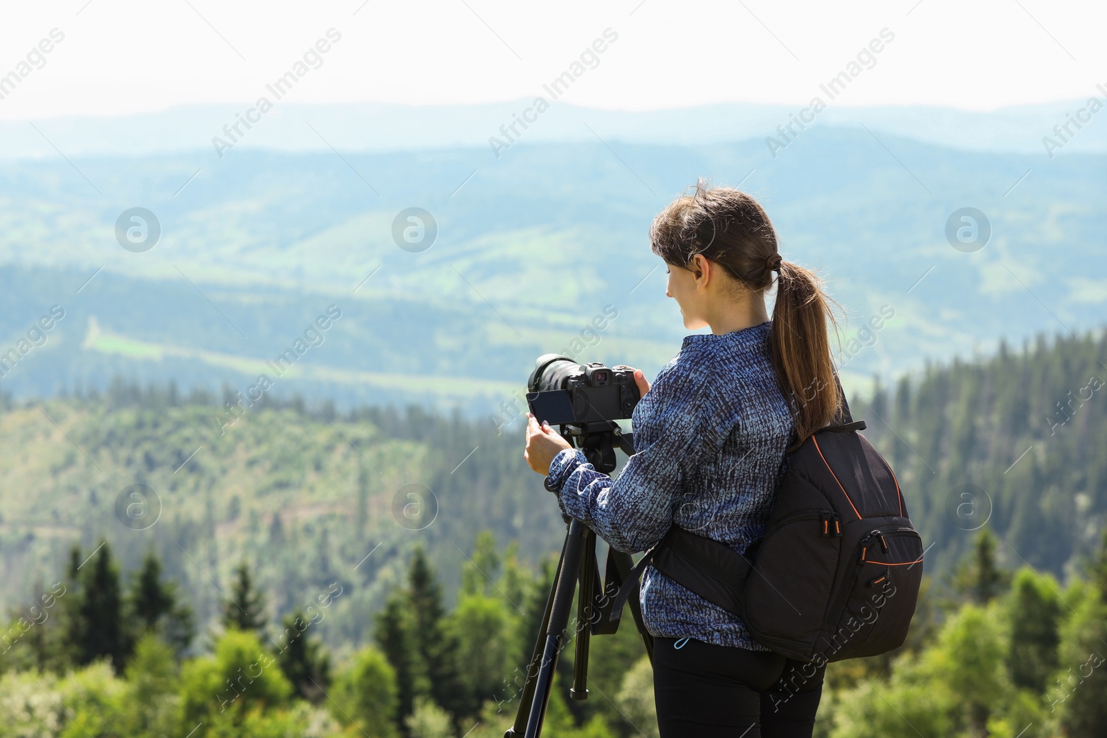 Photo of Photographer with backpack and camera on tripod taking picture of beautiful mountains. Space for text