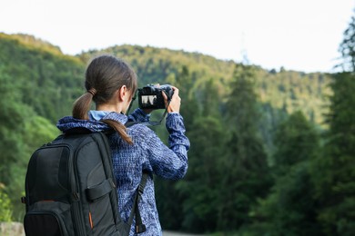 Photo of Photographer with backpack and camera taking picture of beautiful mountains. Space for text