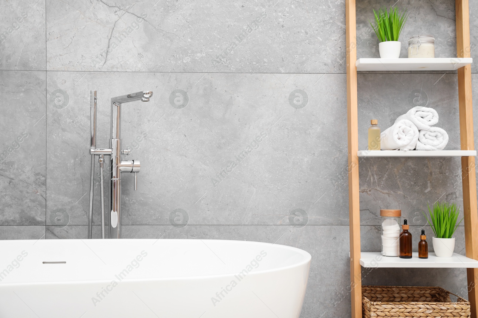 Photo of Bath tub and shelf near light grey wall in bathroom