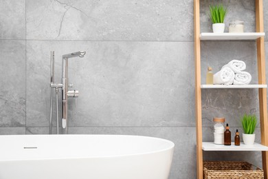 Photo of Bath tub and shelf near light grey wall in bathroom