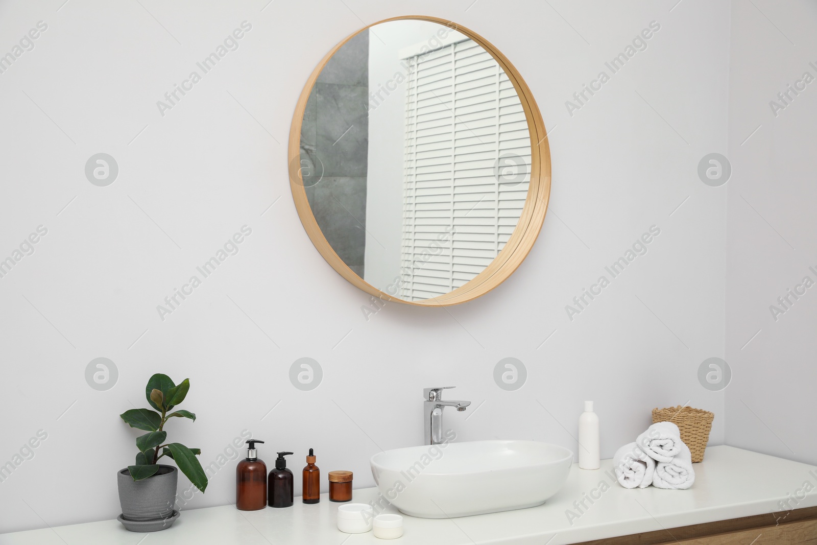 Photo of Countertop with sink, towels, houseplant and mirror in bathroom