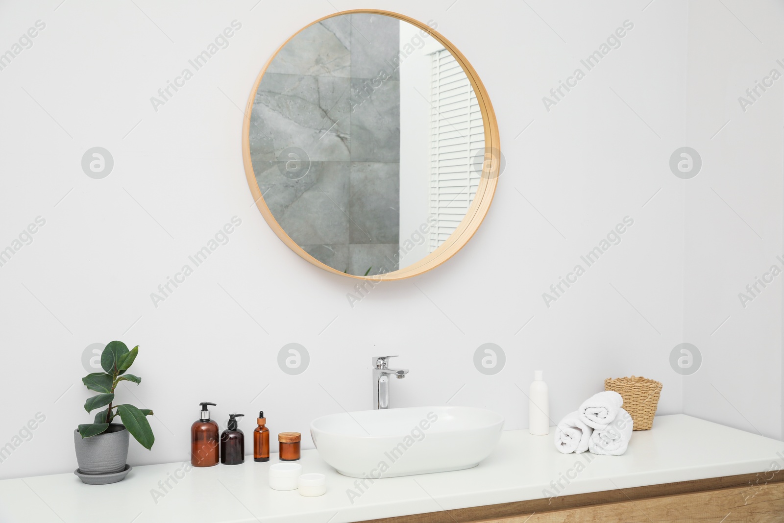 Photo of Countertop with sink, towels, houseplant and mirror in bathroom