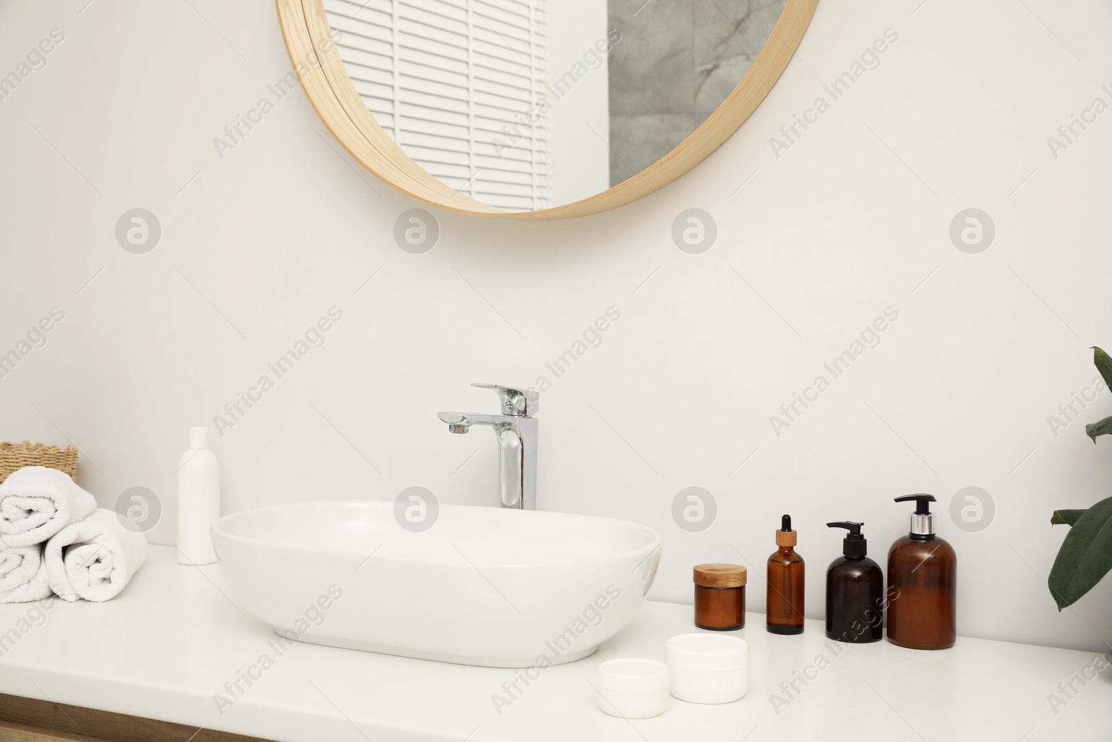 Photo of Countertop with sink, towels, houseplant and mirror in bathroom