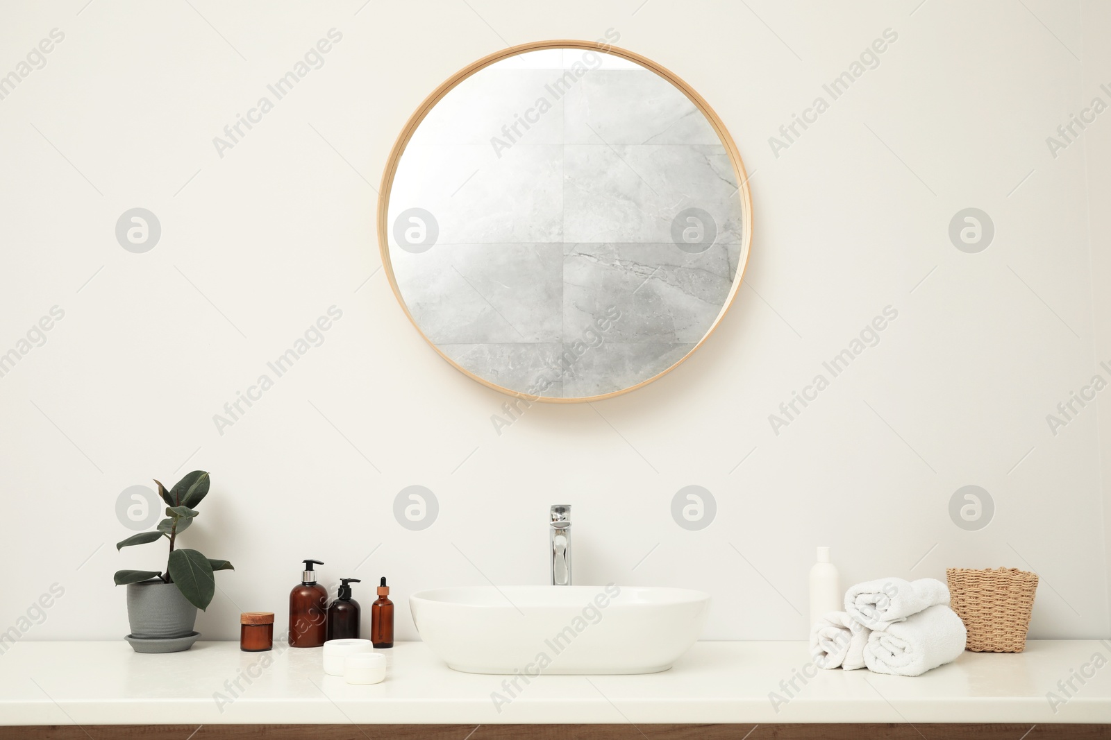 Photo of Countertop with sink, towels, houseplant and mirror in bathroom