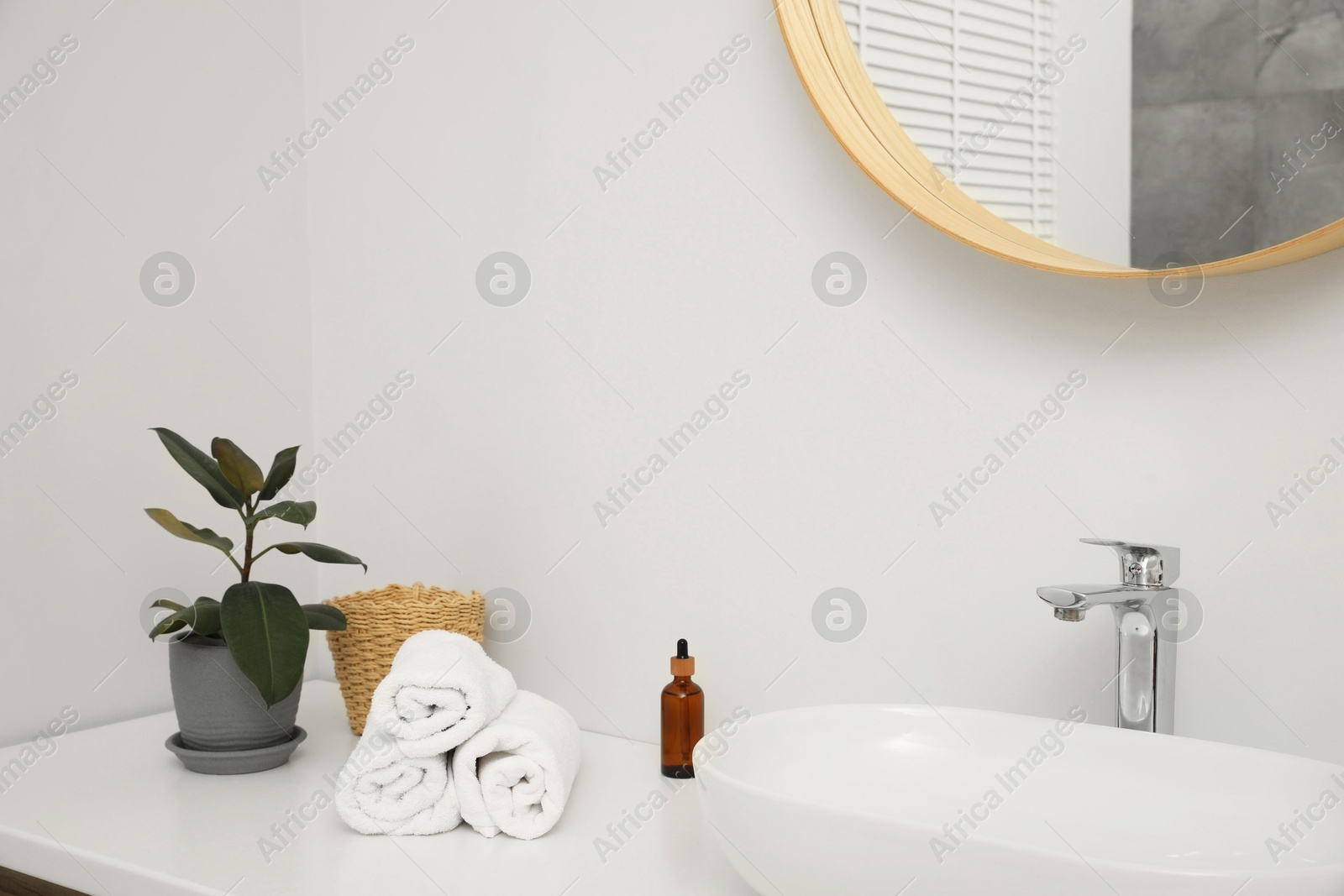 Photo of Countertop with sink, towels, houseplant and mirror in bathroom