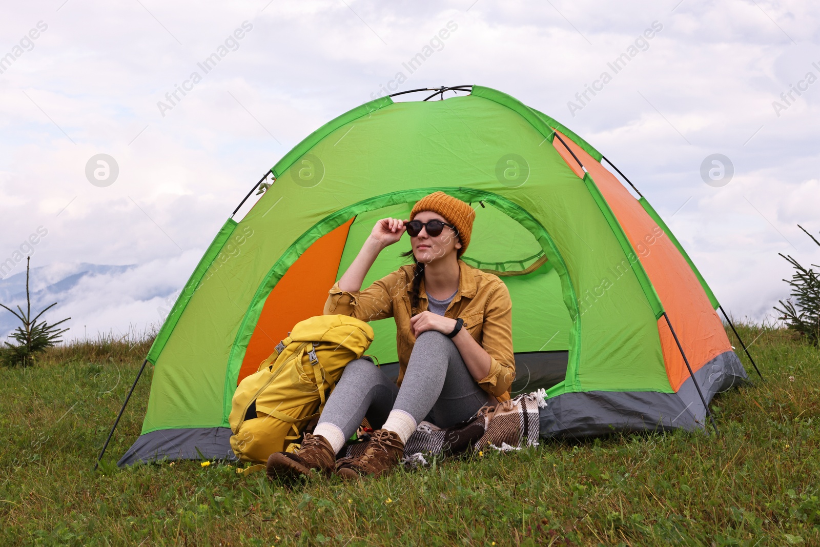 Photo of Young camper and tent in mountains. Active tourism