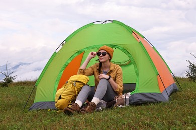 Photo of Young camper and tent in mountains. Active tourism