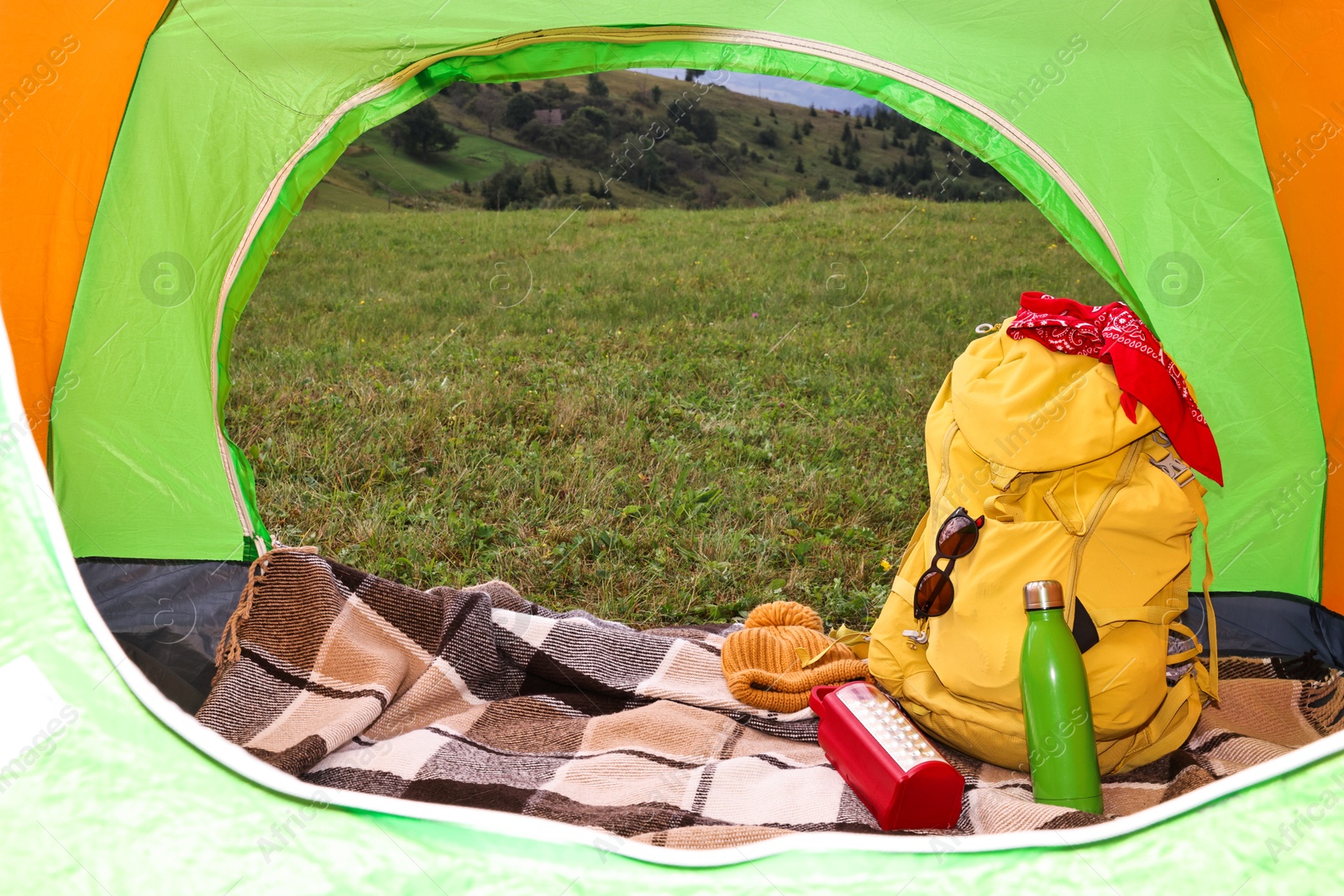 Photo of Tent, backpack and camping equipment on green grass in mountains