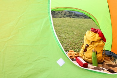 Photo of Tent, backpack and camping equipment on green grass in mountains