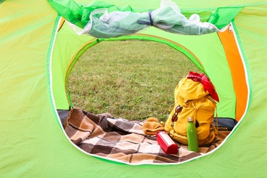 Tent, backpack and camping equipment on green grass in mountains