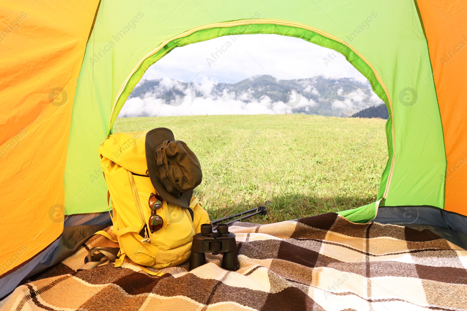 Photo of Tent, backpack and camping equipment on green grass in mountains