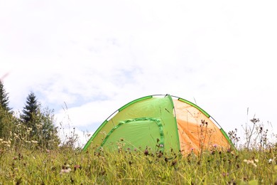 Photo of Tent on green grass in mountains. Camping equipment