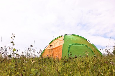 Photo of Tent on green grass in mountains. Camping equipment