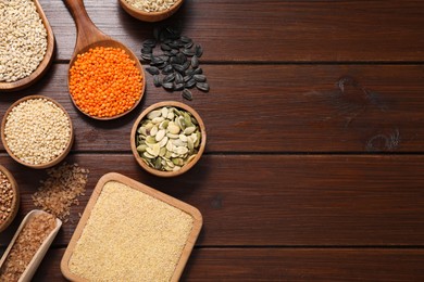 Photo of Different types of cereals, seeds and legumes on wooden table, flat lay. Space for text