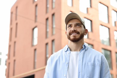 Portrait of smiling man in baseball cap outdoors. Space for text