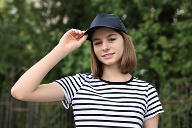 Photo of Portrait of smiling woman in baseball cap outdoors