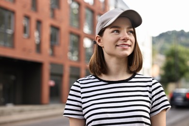 Photo of Portrait of smiling woman in baseball cap outdoors. Space for text