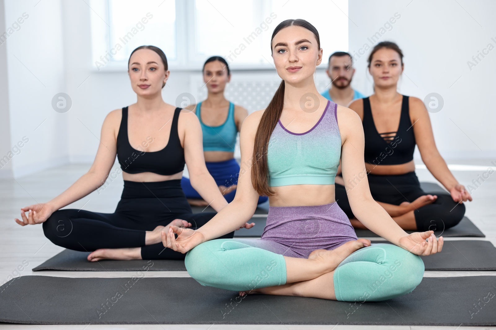 Photo of Group of people meditating on mats in yoga class