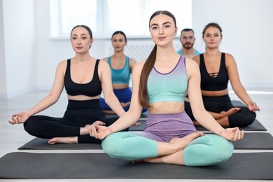 Photo of Group of people meditating on mats in yoga class