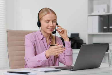 Photo of Interpreter in headset having video chat via laptop at table indoors