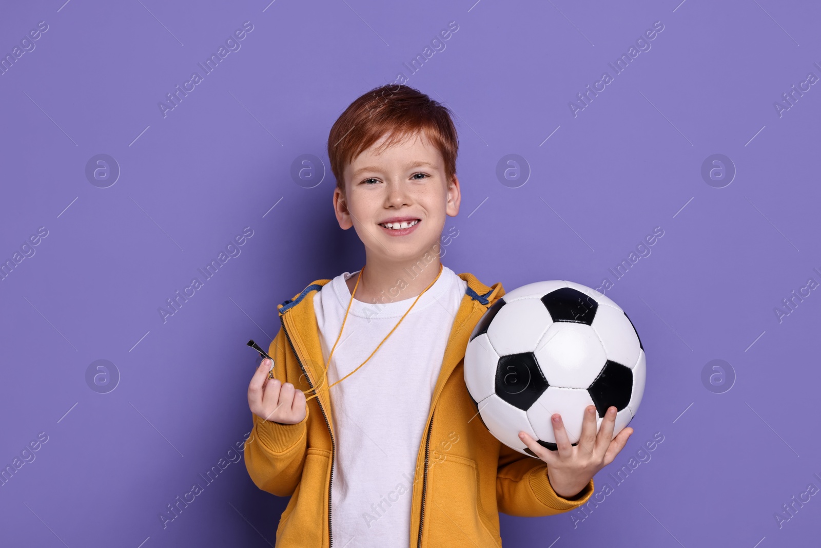 Photo of Little boy with whistle and soccer ball on purple background