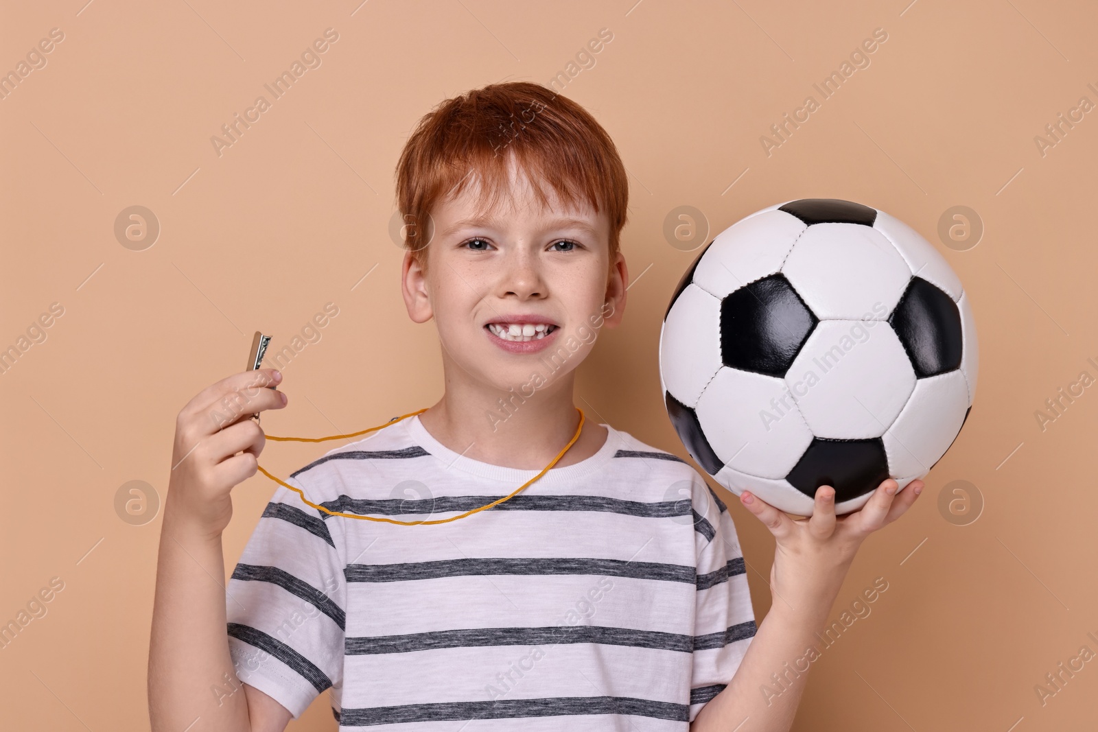 Photo of Little boy with soccer ball and whistle on beige background