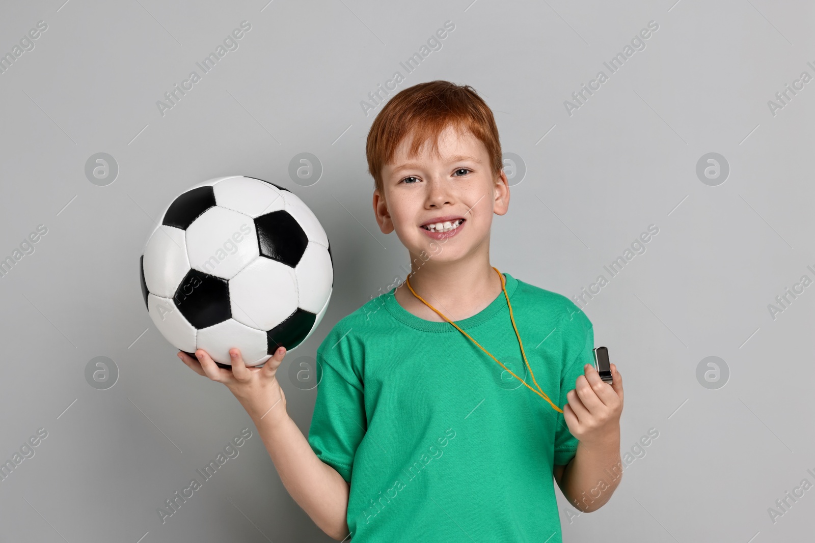 Photo of Little boy with whistle and soccer ball on grey background